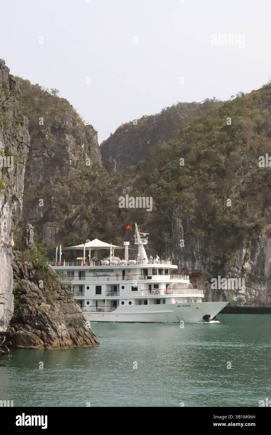 Boot, das hinter einer Klippe in Lan Ha Bay, Vietnam, auftaucht. Stockfoto