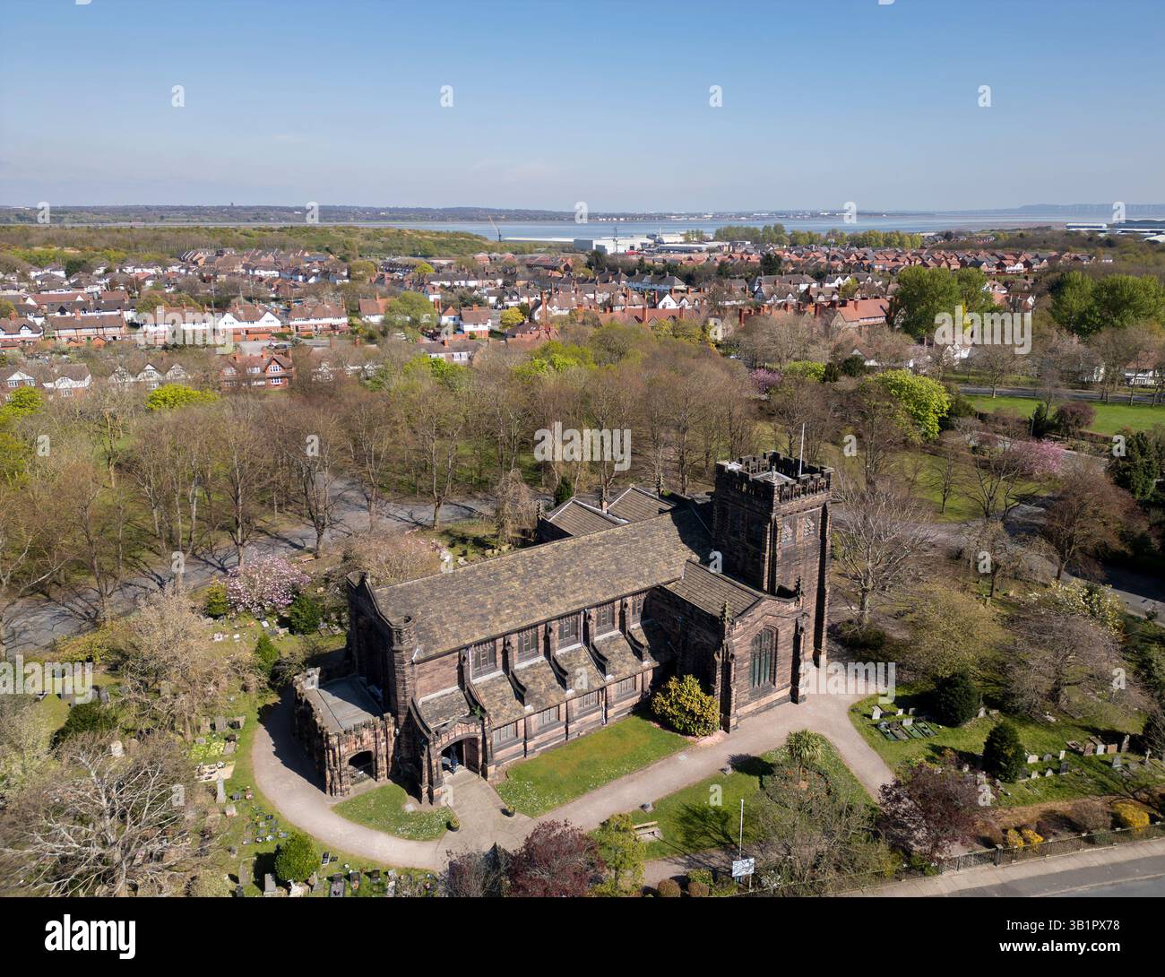 WIRRAL, MERSEYSIDE, ENGLAND - 9. APRIL 2025: Luftaufnahme der Christ Church in Port Sunlight, Wirral mit dem Fluss Mersey im Hintergrund, England Stockfoto