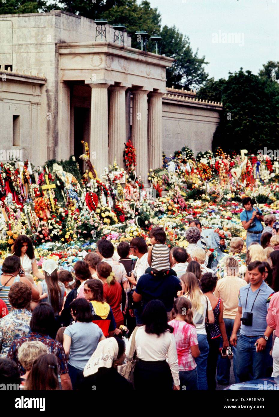 August 1977 - Memphis, TN, USA - Forest Hill Cemetery Midtown 19. August 1977. Mehr als 50.000 Fans, von denen einige eine nächtliche Mahnwache an den Toren des Friedhofs hielten, gingen die letzte Meile, um Elvis Presley Tribut zu zollen, und gingen mit den Blumen, die sein Mausoleum am Hügel säumten. Mehr als 3.000 Blumenarrangements wurden auf dem Mausoleum-Rasen verteilt. (Kreditbild: © The Commercial Appeal/ZUMApress.com) Stockfoto August 1977 - Memphis, TN, USA - Forest Hill Cemetery Midtown 19. August 1977. Mehr als 50.000 Fans, von denen einige eine nächtliche Mahnwache an den Toren des Friedhofs hielten, gingen die letzte Meile, um Elvis Presley Tribut zu zollen, und gingen mit den Blumen, die sein Mausoleum am Hügel säumten. Mehr als 3.000 Blumenarrangements wurden auf dem Mausoleum-Rasen verteilt. (Kreditbild: © The Commercial Appeal/ZUMApress.com) Stockfoto