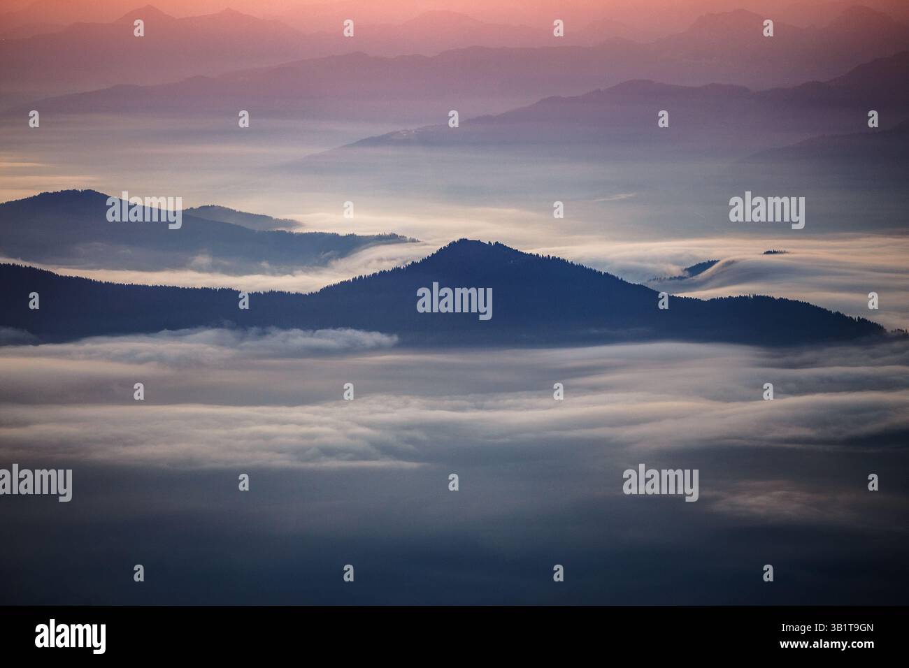 Stimmungsvolle Berglandschaft bei Sonnenaufgang. Wolkenflut über dem Tal. Hügel und Berggipfel. Österreichische Alpen. Europa. Stockfoto