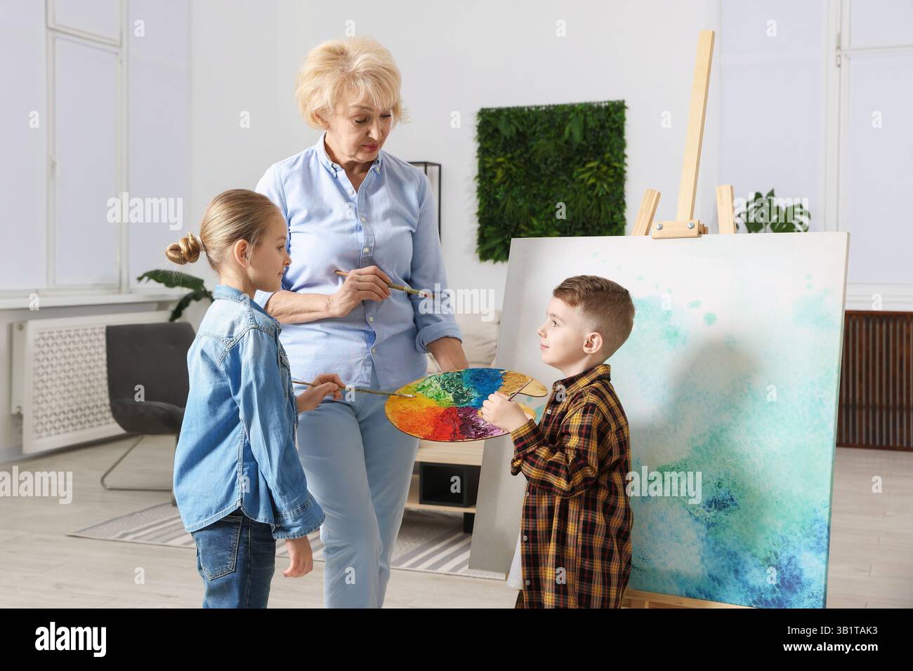 Großmutter und ihre Enkel malen zusammen zu Hause Stockfoto