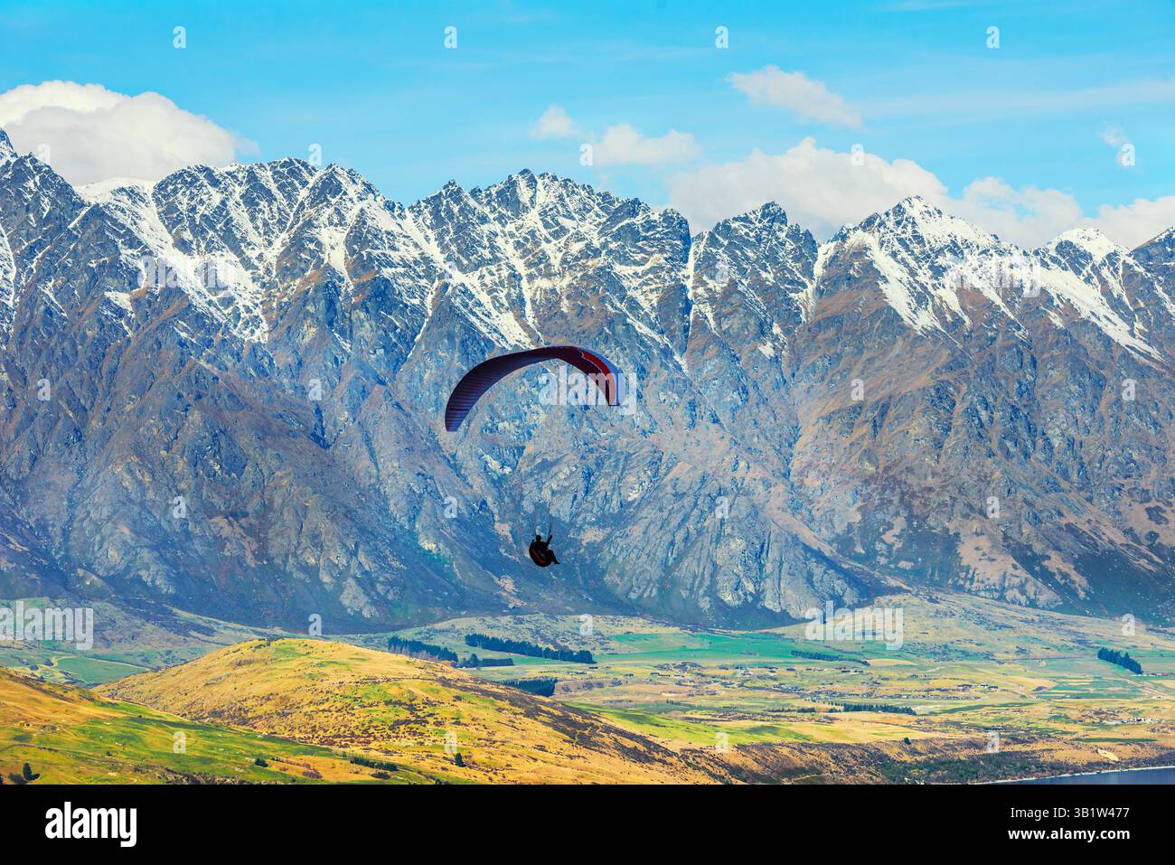 Gleitschirmfliegen in der Nähe der schneebedeckten Remarkables Bergkette, Queenstown, Südinsel, Neuseeland Stockfoto