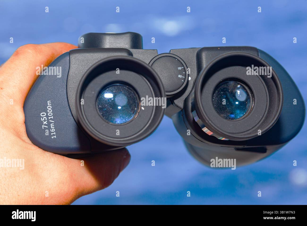 Männliche Hand hält ein optisches Fernglas in Richtung Meer. Stockfoto