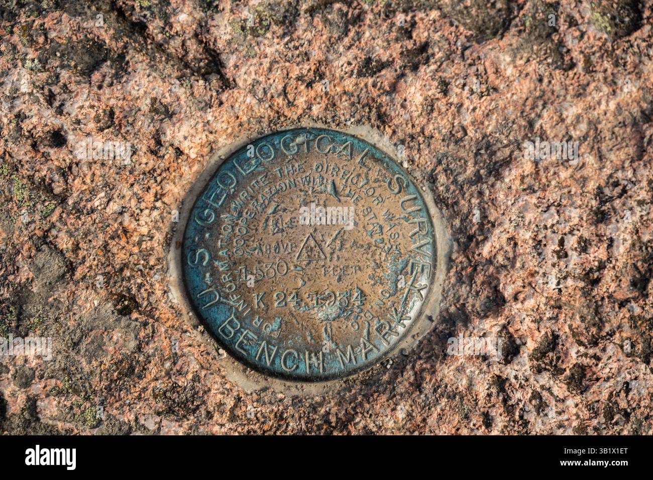 Benchmark für geologische Messungen eingebettet in Felsen in Acadia Stockfoto