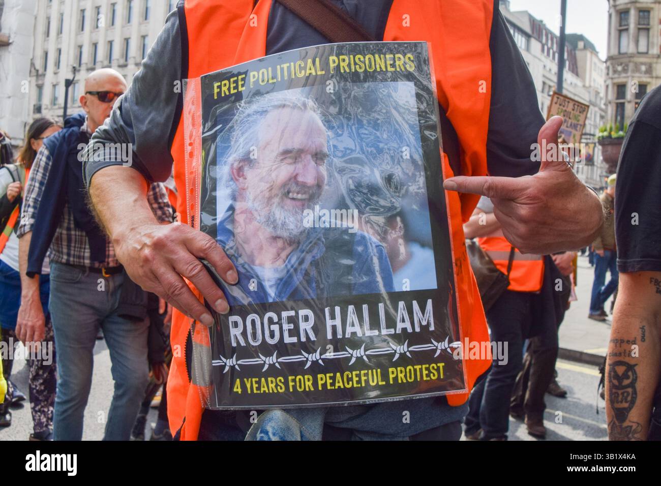 London, Großbritannien. April 2025. Ein Just Stop Oil-Aktivist hält ein Schild, das die Freilassung der Gefängnisauslöschungs-Rebellion und Just Stop Oil-Mitbegründer Roger Hallam fordert, während JSO ihren letzten Protest inszeniert. Die Klimagruppe kündigte kürzlich an, die Protestaktionen einzustellen. Quelle: Vuk Valcic/Alamy Live News Stockfoto