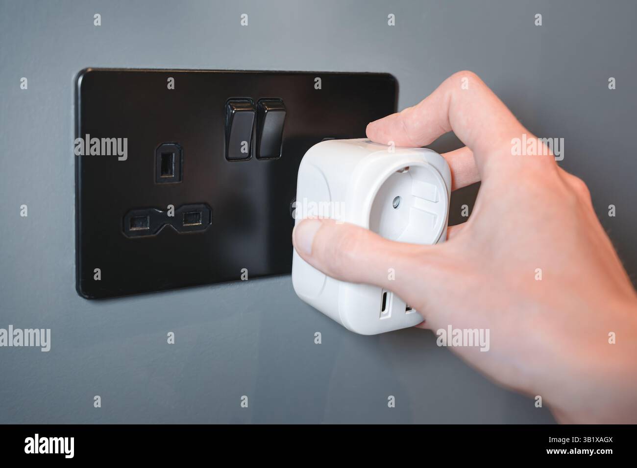 Reisende stecken einen europäischen Adapter in eine UK-Buchse im Hotelzimmer, Reisezubehör Stockfoto