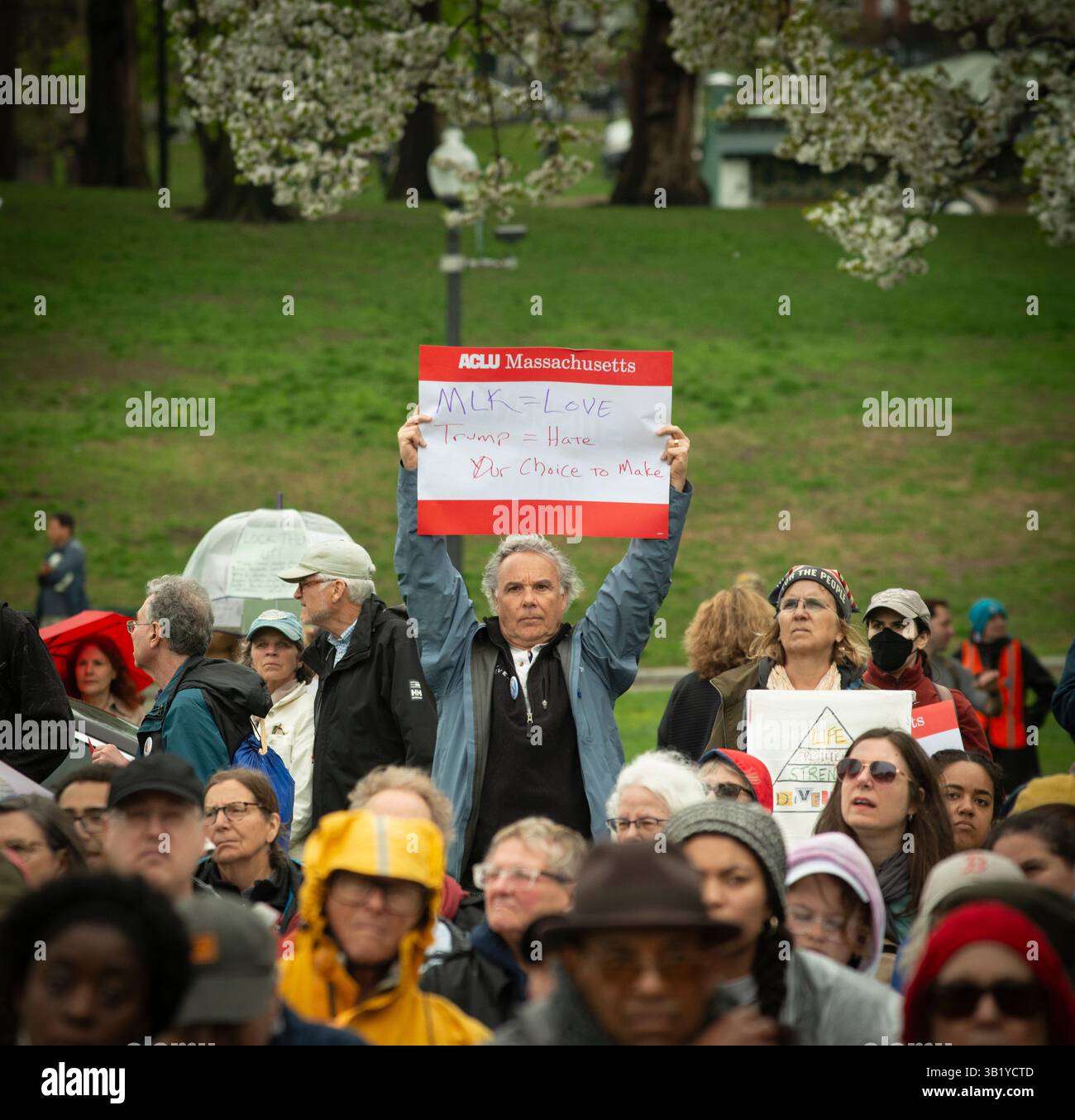 Boston, Massachusetts, USA. 26. April 2025. 60. Jahrestag des Boston Freedom March 1965. Man hält ein Schild mit Bezug auf Martin Luther King Jr. (MLK) in der Menge am Parkman-Bandstand zu Beginn der Gedenkfeier an der Boston Common. Martin Luther King Jr. (1929–1968) war einer der Führer der Freedom March Credit: Chuck Nacke / Alamy Live News von 1965 Stockfoto