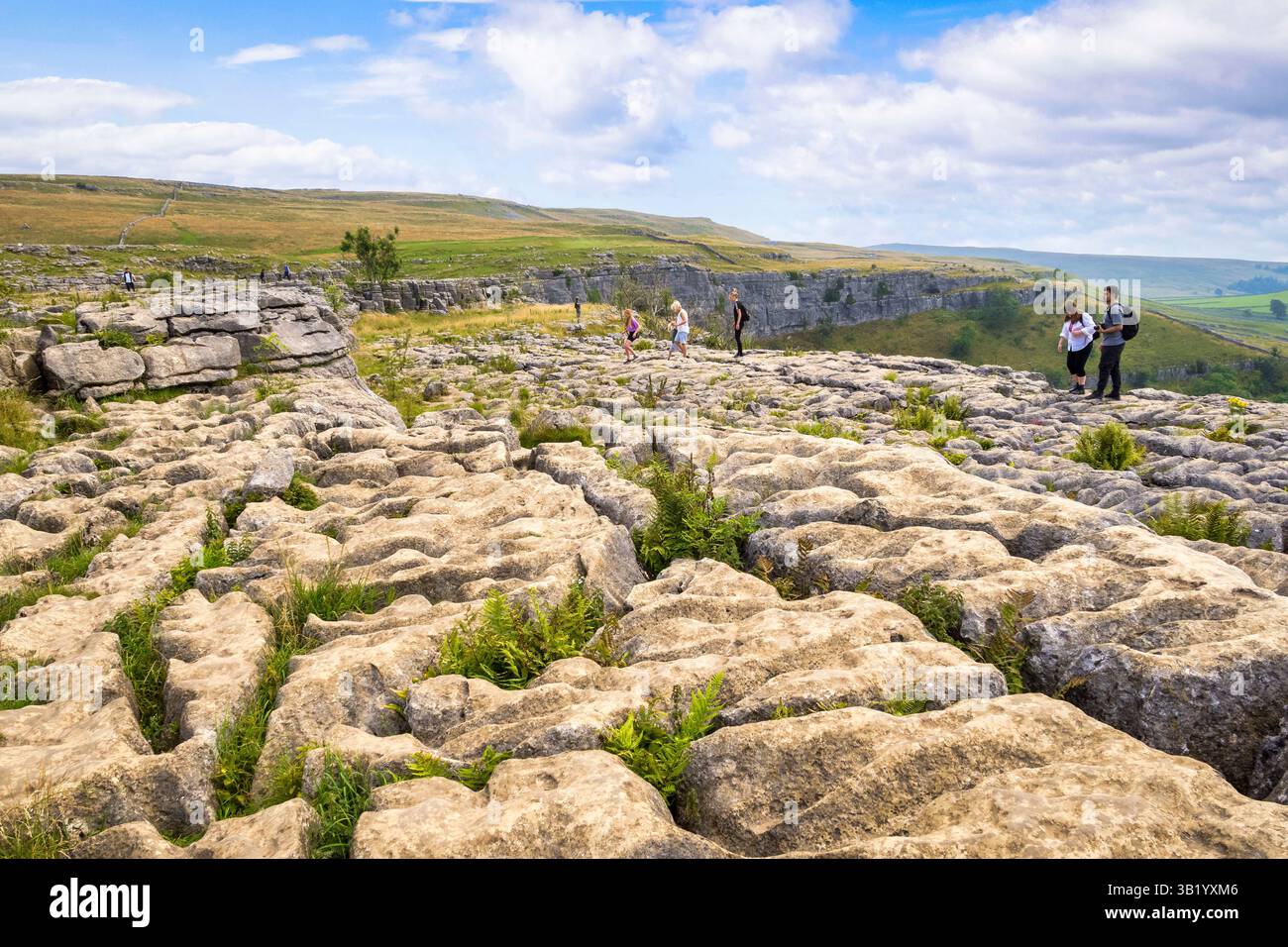 2. August 2024: Malham Cove, Yorkshire Dales National Park, Vereinigtes Königreich - Kalksteinkarst, oder Kalksteinpflaster, auf der Spitze der Bucht. Leute, die herumlaufen Stockfoto
