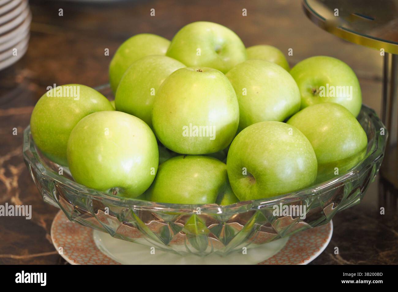 Frische grüne Äpfel in einer Kristallschale auf einer Arbeitsplatte angeordnet Stockfoto