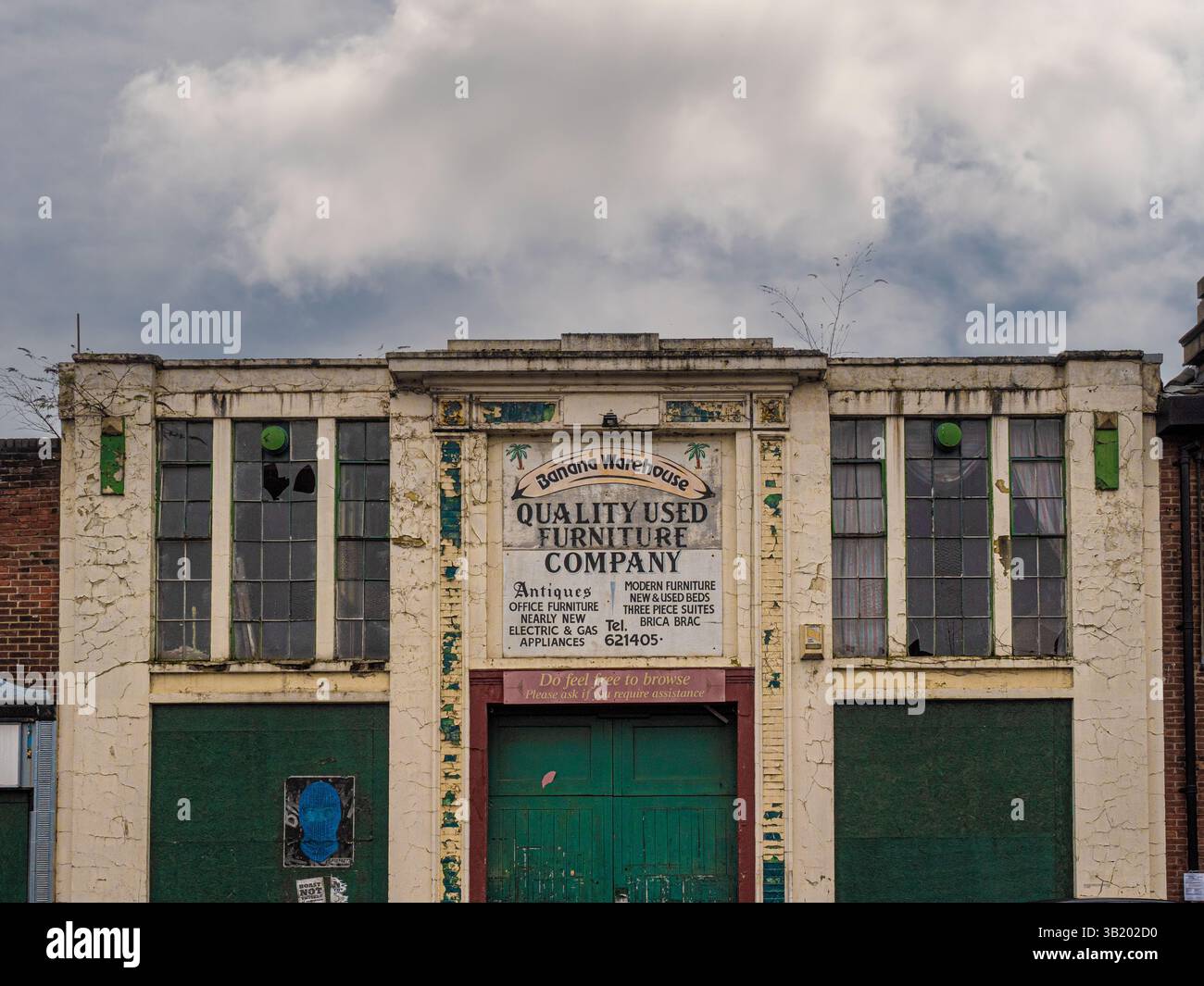 Verfallenes Banana Warehouse Gebäude in York, ehemals Sitz eines gebrauchten Möbelgeschäfts, mit Rissen in der Farbe, kaputten Fenstern und verblassten Schildern auf einer bewölkten Oberfläche Stockfoto