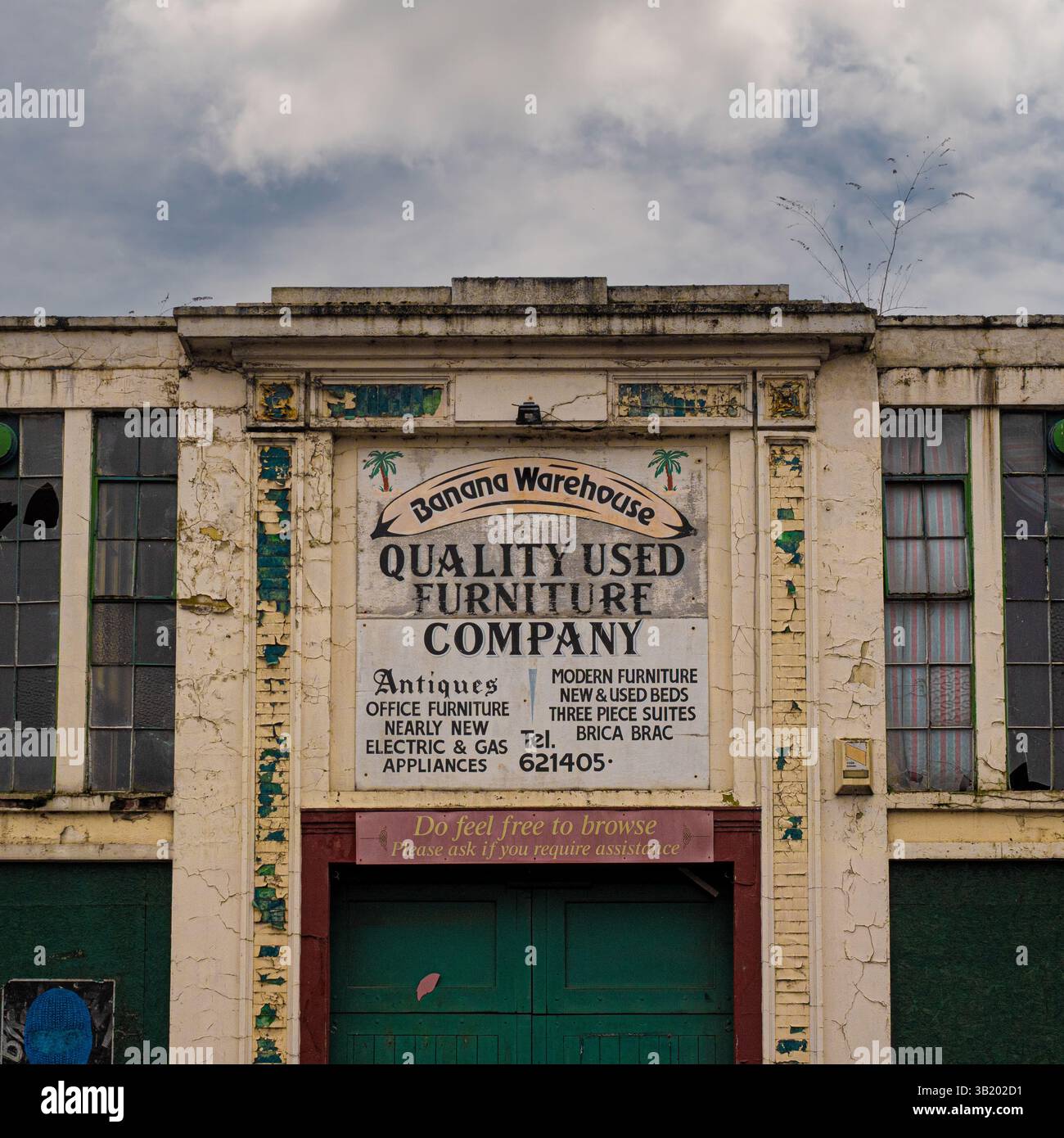 Verfallenes Banana Warehouse Gebäude in York, ehemals Sitz eines gebrauchten Möbelgeschäfts, mit Rissen in der Farbe, kaputten Fenstern und verblassten Schildern auf einer bewölkten Oberfläche Stockfoto