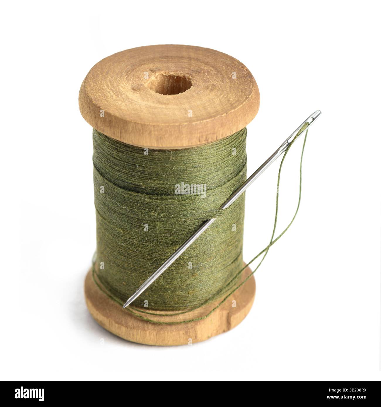 Alte einzelne Holzspule des Garns olivgrüne Farbe und Nadel einfaches Design des Garns Nahaufnahme weißen Hintergrund Stockfoto