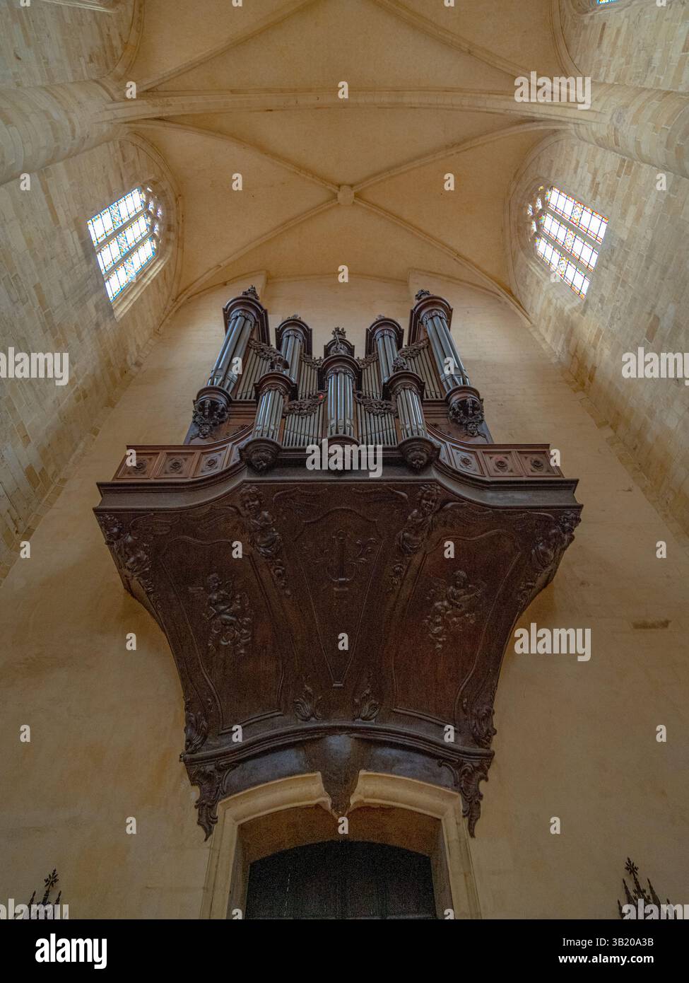 Flacher Blick auf die große hölzerne Orgel in einer einfachen, gut beleuchteten gotischen Kirche in Südwestfrankreich ohne Menschen Stockfoto