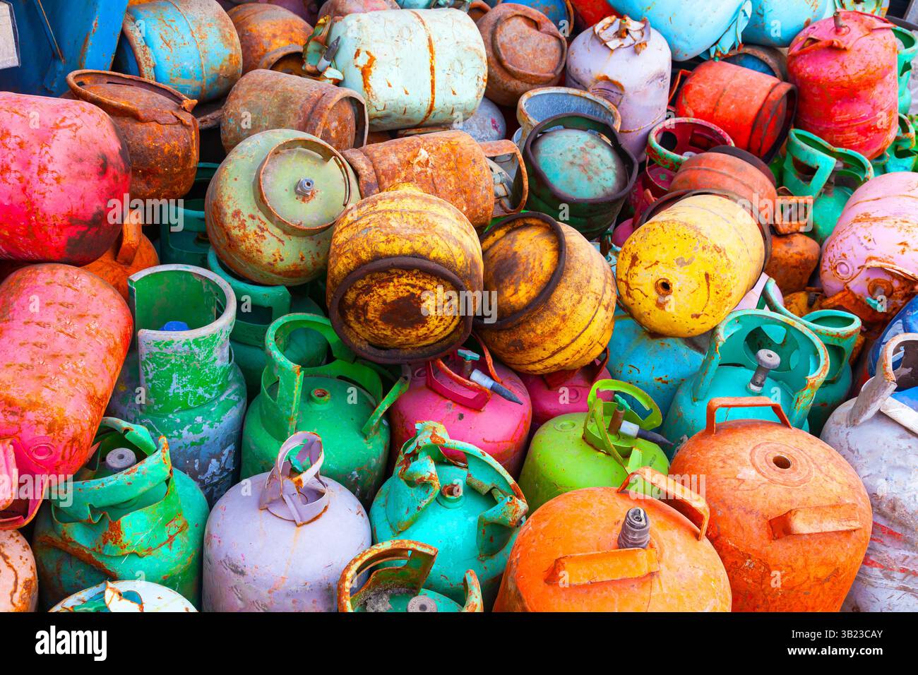 Ein Haufen alter gebrauchter, mehrfarbiger Gasflaschen kleiner Größe. Metallschrott aus Gasflaschen. Stockfoto