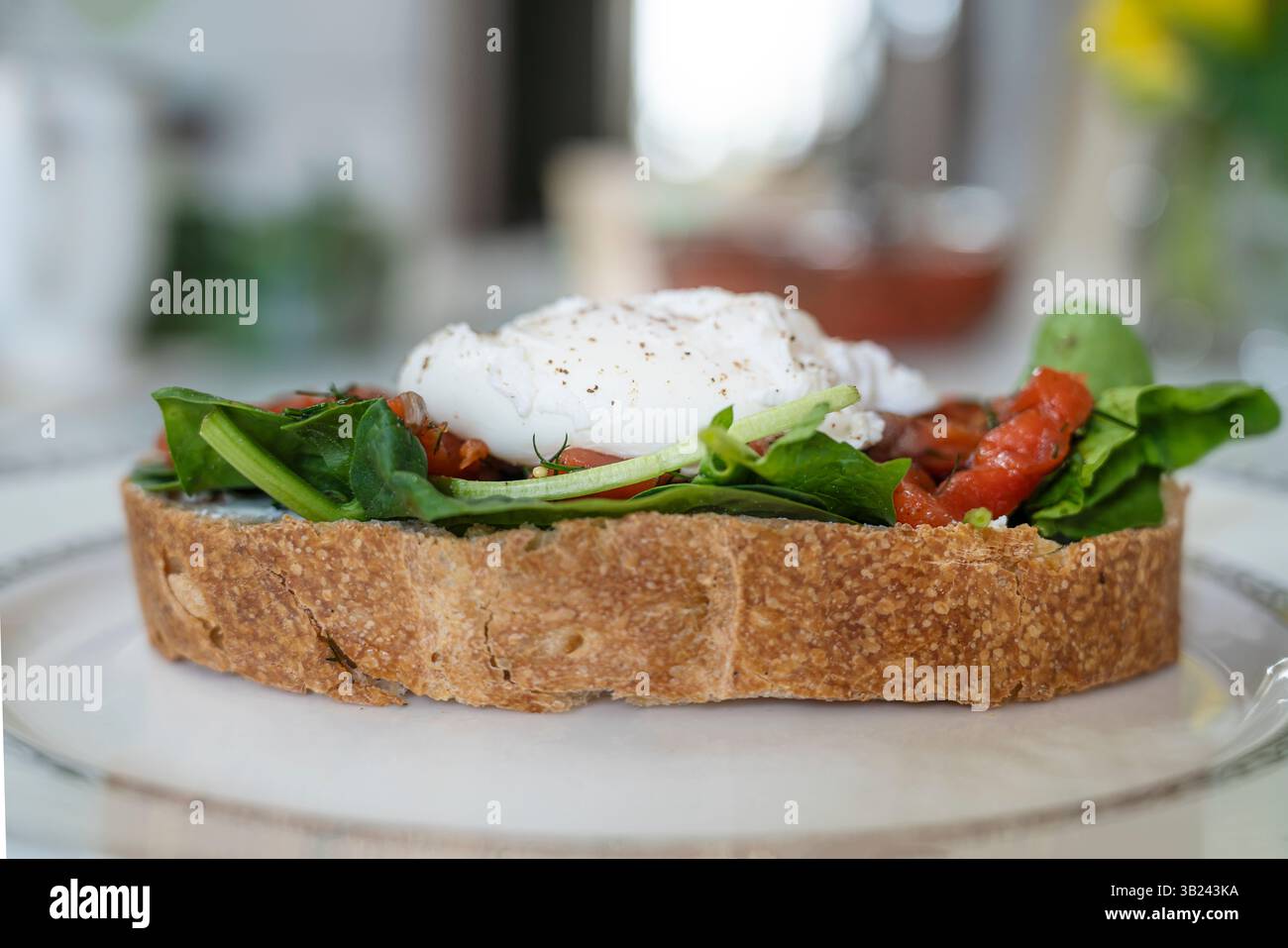 Ein köstliches Frühstück mit pochiertem Ei auf einer Scheibe Ciabatta mit Spinat und Stücken rot gesalzenem Fisch Stockfoto