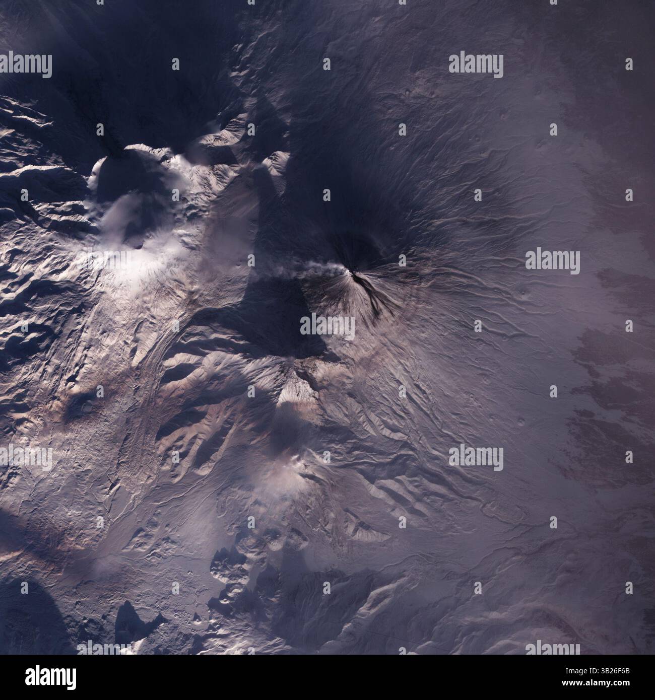 11. Dezember 2009 - Kamtschatka-Halbinsel, Russland - Dunkle Lava fließt entlang der Südostflanke des Klyuchevskaja-Vulkans in diesem Satellitenbild. Die dunkelgraue Lava - vielleicht kombiniert mit Ablagerungen von Laharen oder pyroklastischen Strömungen - steht in starkem Kontrast zu den schneebedeckten und sonnendurchfluteten Südhängen des Vulkans, während sich eine dünne Wolke genau westlich vom Gipfel erstreckt. Laut Smithsonian/USA Das Geological Survey Global Volcanism Program, Klyuchevskaja, war während des größten Teils des Jahres 2009 aktiv. Das Advanced Spaceborne Thermal Emissions- und Reflexionsradiometer an Bord des Satelliten Terra der NASA hat dieses fals gefangen genommen Stockfoto