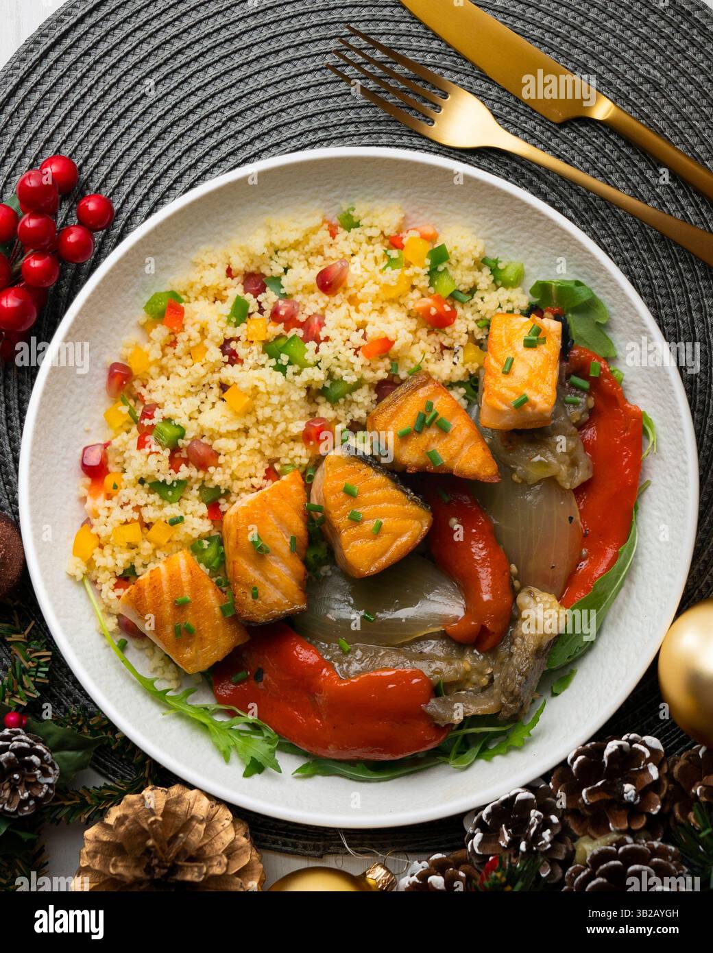 Gericht mit gebackenem Lachs, Paprika und Couscous-Salat. Tisch mit Blick von oben mit weihnachtsdekoration. Stockfoto