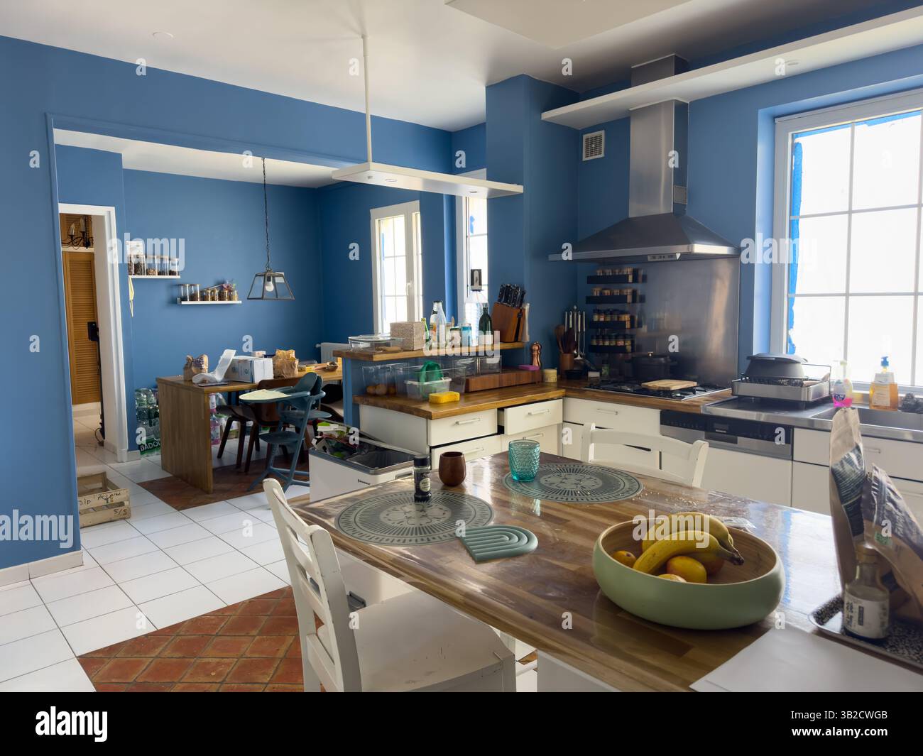 Der helle und lebendige Küchenbereich bietet eine einladende Atmosphäre mit blauen Wänden und modernen Möbeln, perfekt für Versammlungen Stockfoto