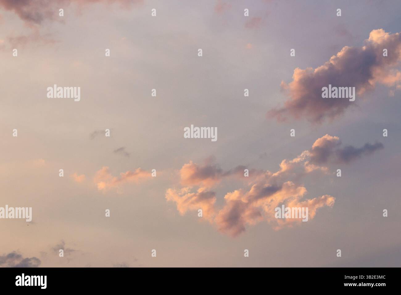 cumulus Wolken am Himmel, vom Wind geweht. Meditation in der Abenddämmerung. Trübe Wettermeteorologie-Hintergrund bei orangenem Schein. Abendstimmung Stockfoto