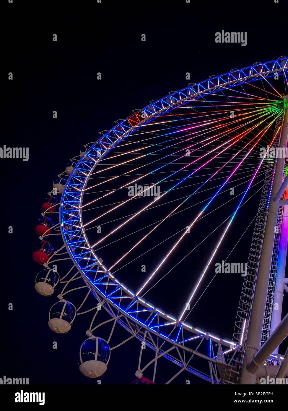 Beleuchtetes Riesenrad bei Nacht mit bunten LED-Lichtern vor dunklem Himmel Stockfoto