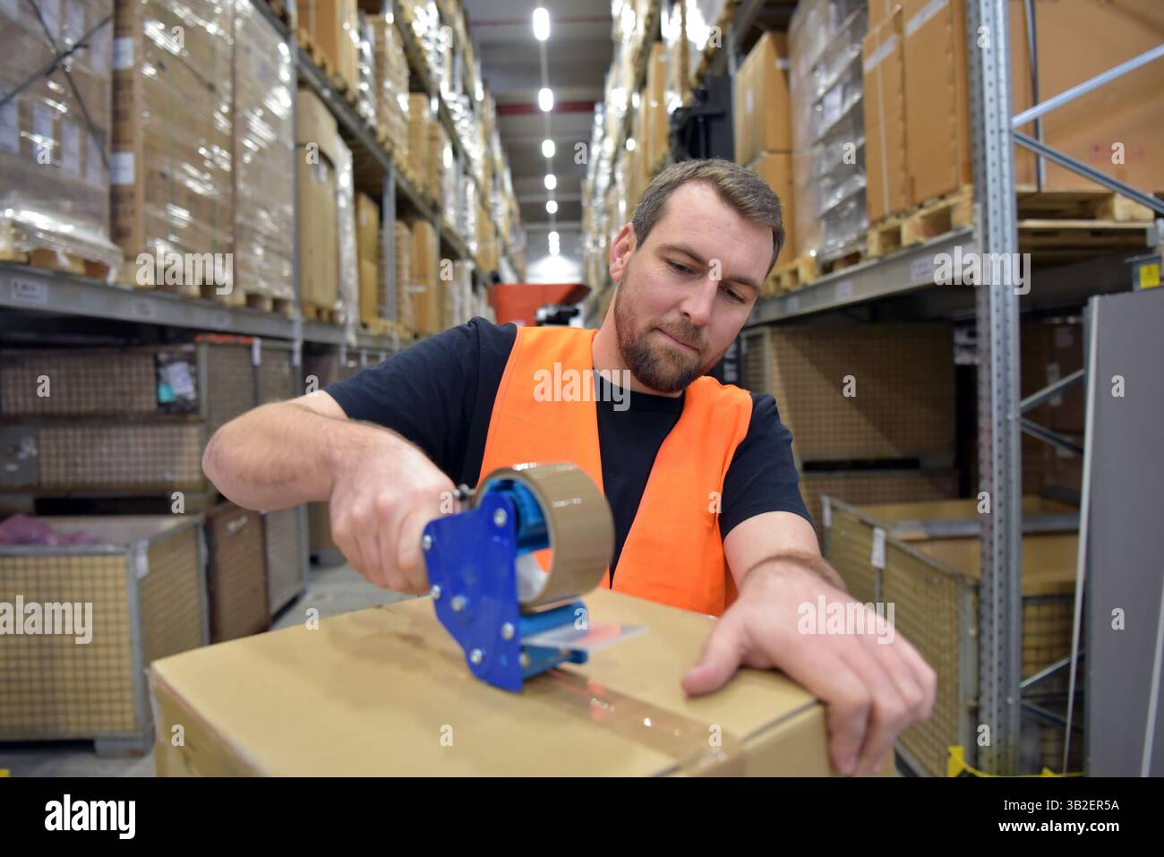 Arbeiter in einem Warenlager im Einzelhandel verpackten ein Paket mit Klebeband Stockfoto