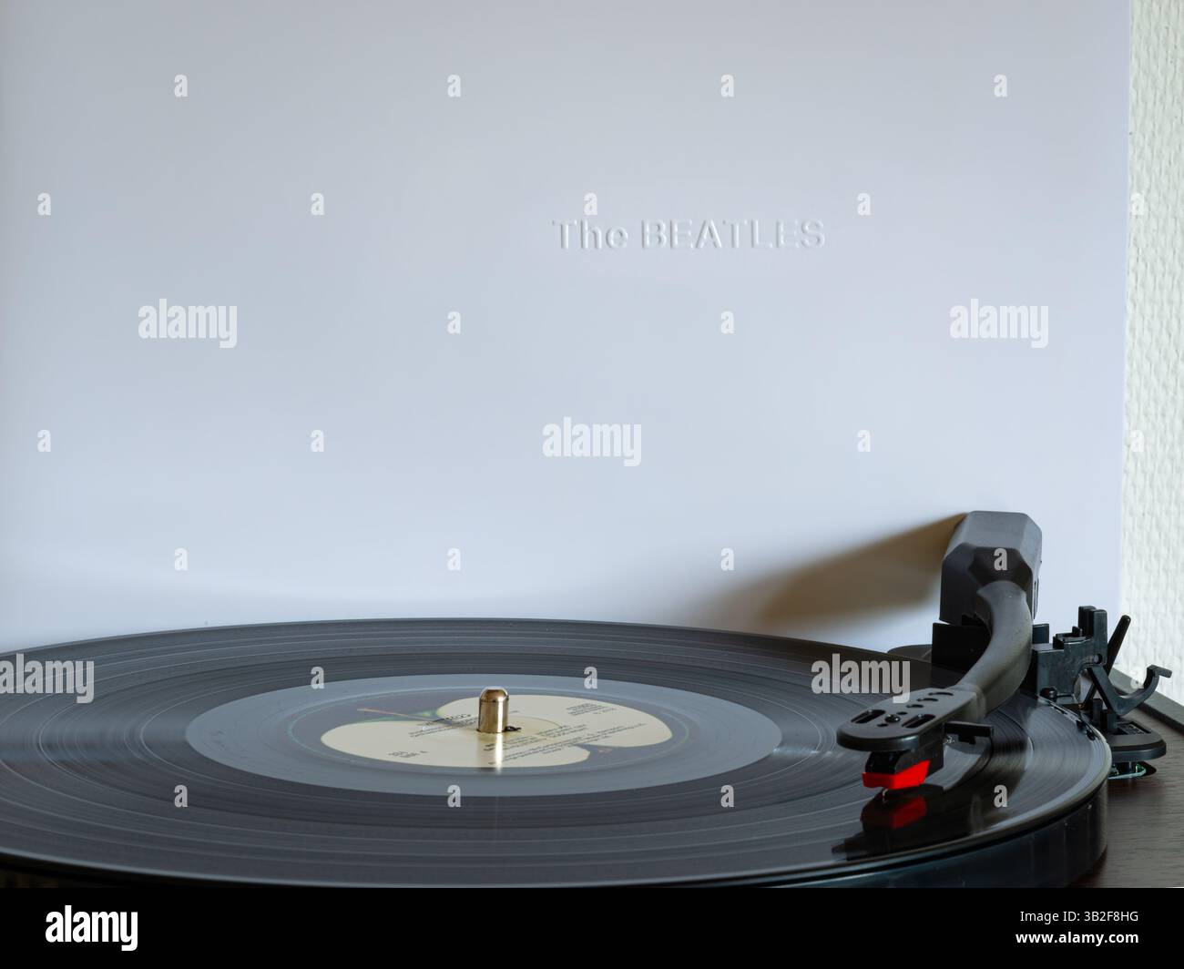 Plattenspieler mit Aufnahme aus dem Album ¨The Beatles¨ der gleichnamigen Rockband. Cover aus dem weißen Album im Hintergrund. Stockfoto