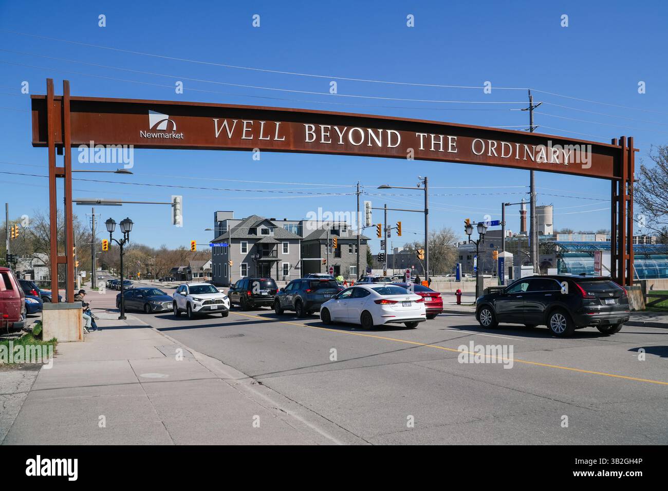 Dieses Bild zeigt das Newmarket-Schild in der Hauptstraße in Ontario, Kanada an einem sonnigen Tag mit Autos und Gebäuden im Hintergrund. Stockfoto