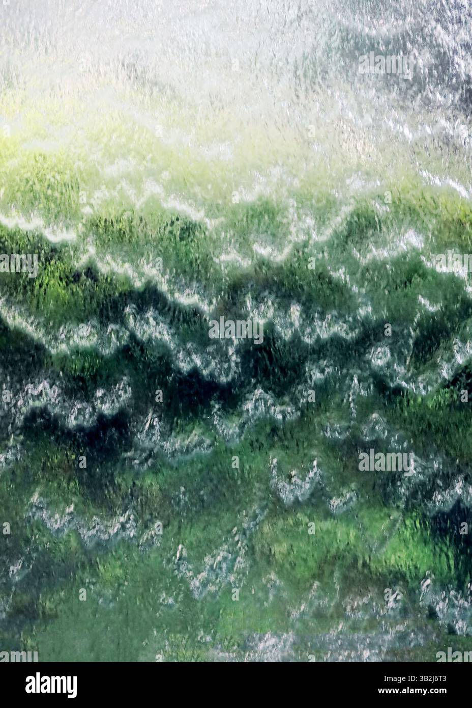 Nahaufnahme eines grün leuchtenden künstlichen Wasserfalls als Hintergrundmaterial Stockfoto