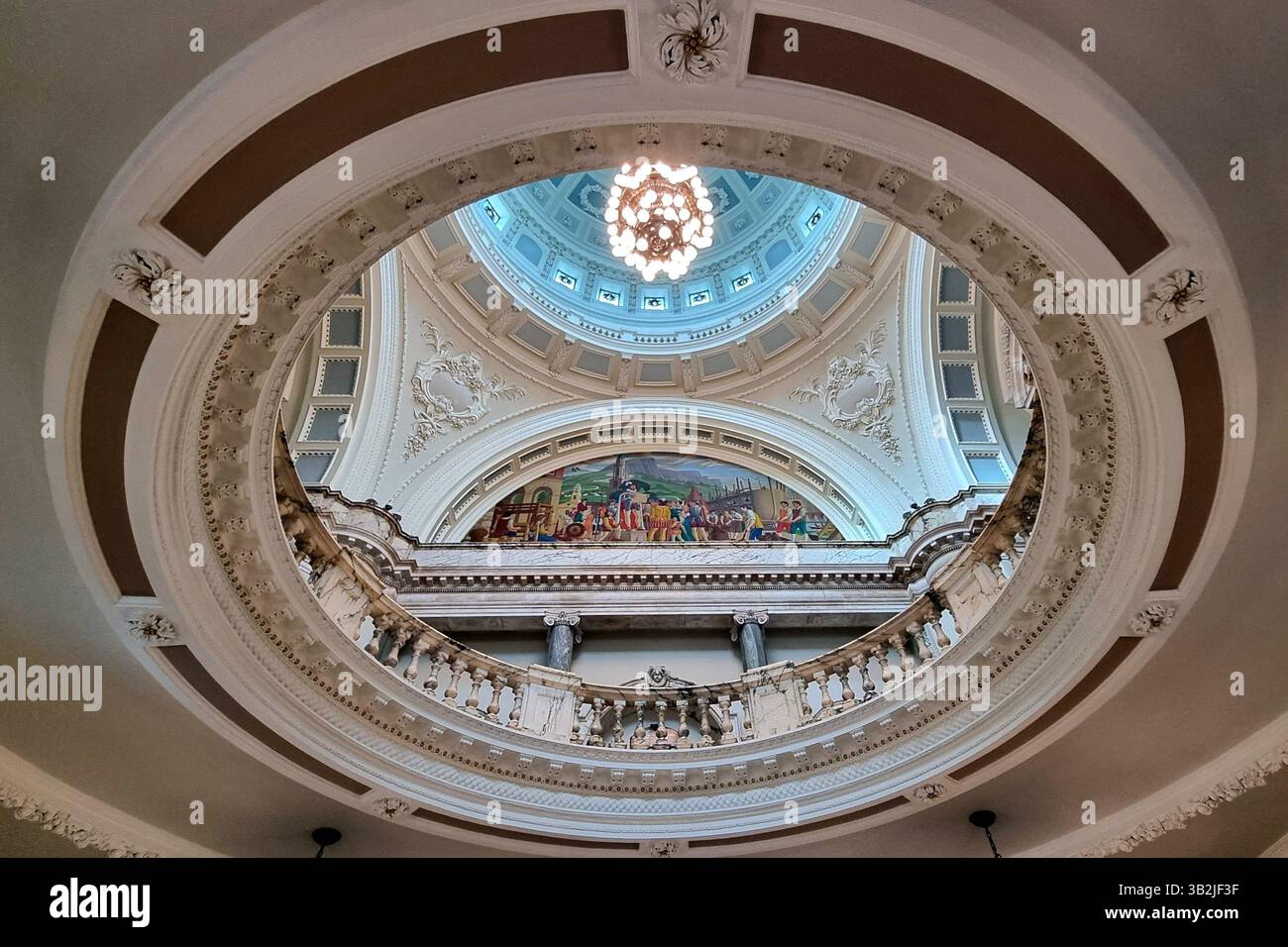 Ein ungewöhnlicher Blick vom Foyer durch die Rotunde mit Balustrade bis zur spektakulären bemalten Kuppeldecke und dem farbenfrohen Wandgemälde im Rathaus von Belfast Stockfoto