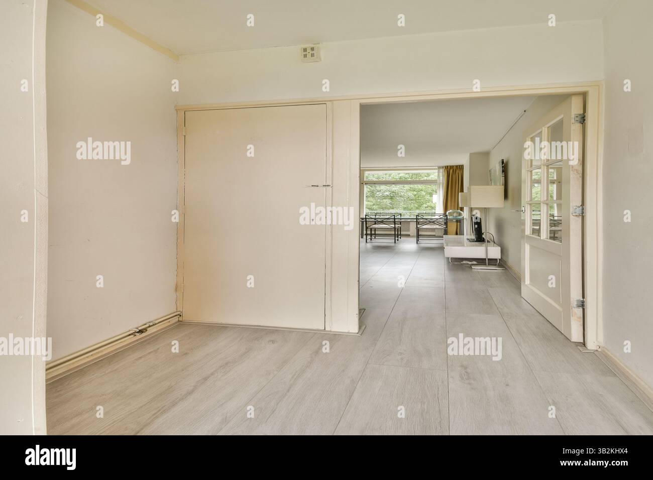 Geräumiger Innenbereich mit sauberer, moderner Ästhetik, neutralen Farben und natürlichem Licht durch große Fenster. Stockfoto