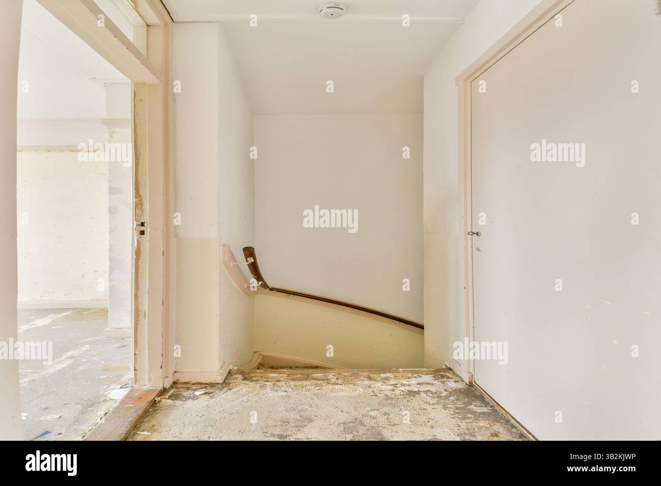 Ein geräumiger Innenraum mit einer Treppe, die zu einem oberen Stockwerk führt, mit neutralen Wänden und natürlichem Licht, das den Bereich beleuchtet und eine einladende Atmosphäre schafft. Stockfoto