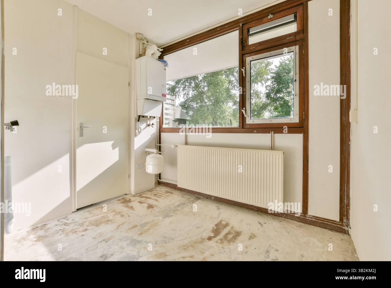 Ein geräumiger, moderner Raum mit großen Fenstern, neutralen Wänden und minimalistischem Design, der viel Tageslicht für eine einladende Atmosphäre bietet. Stockfoto