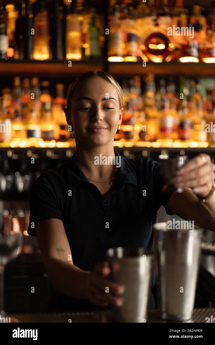 Lächelnde Barkeeperin, die Cocktails an der Bar zubereitet Stockfoto