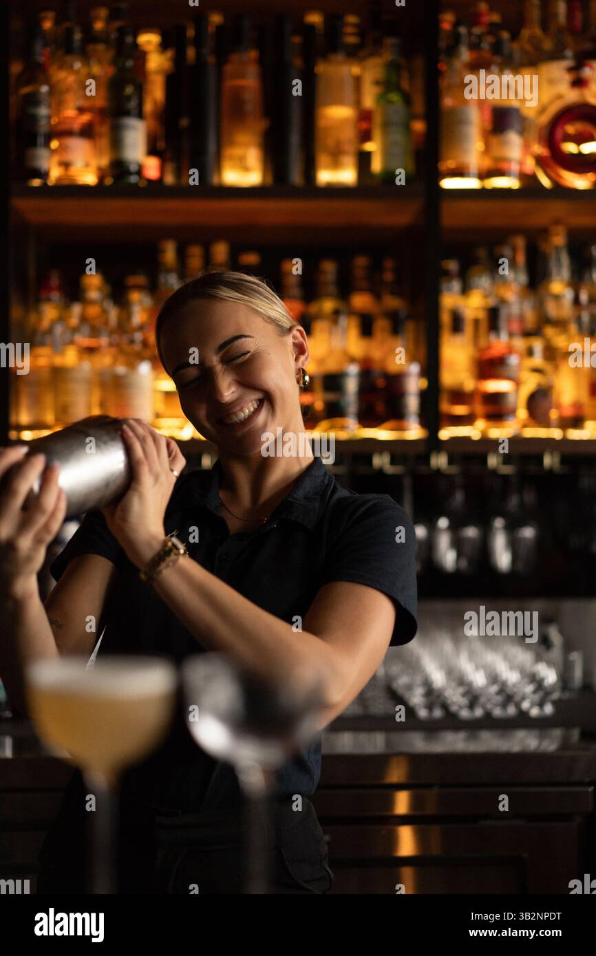 Lächelnde Barkeeperin, die Cocktails an der Bar zubereitet Stockfoto