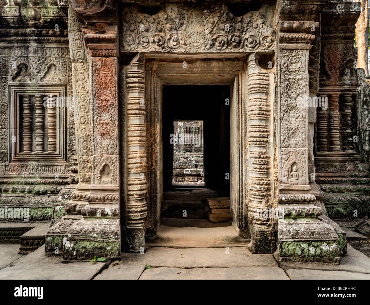 Komplizierte Steinschnitzereien und Eingänge eines antiken Tempels, die detaillierte Architektur und historische Bedeutung zeigen. Die Perspektive führt durch Stockfoto