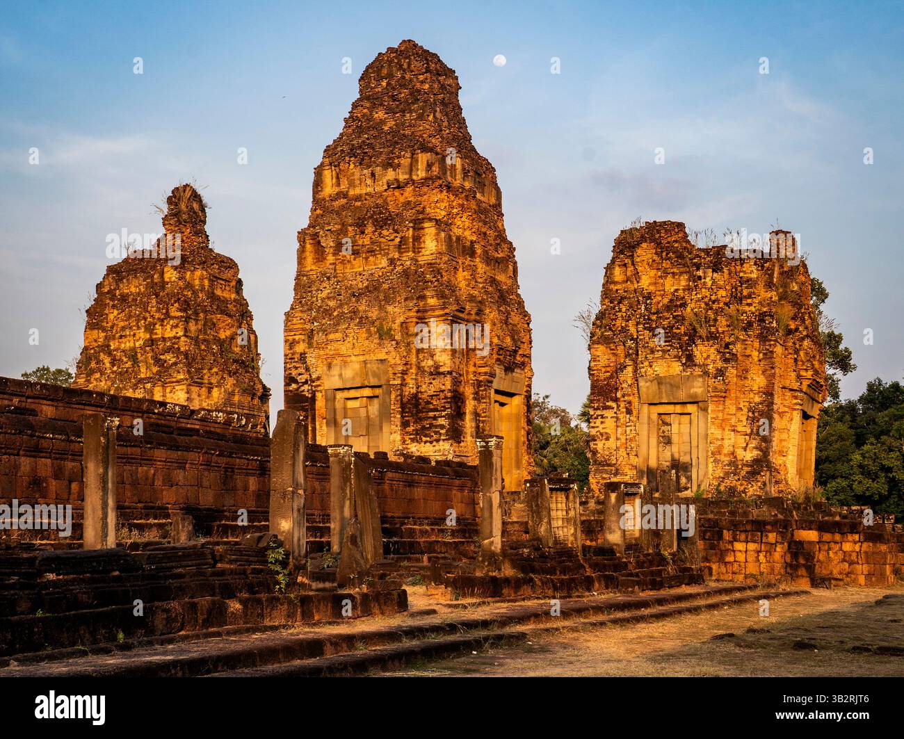 Antike Tempelruinen mit hoch aufragenden Steinstrukturen unter klarem Himmel, mit sichtbarem Mond. Die Szene fängt die Schönheit des historischen Architekten ein Stockfoto