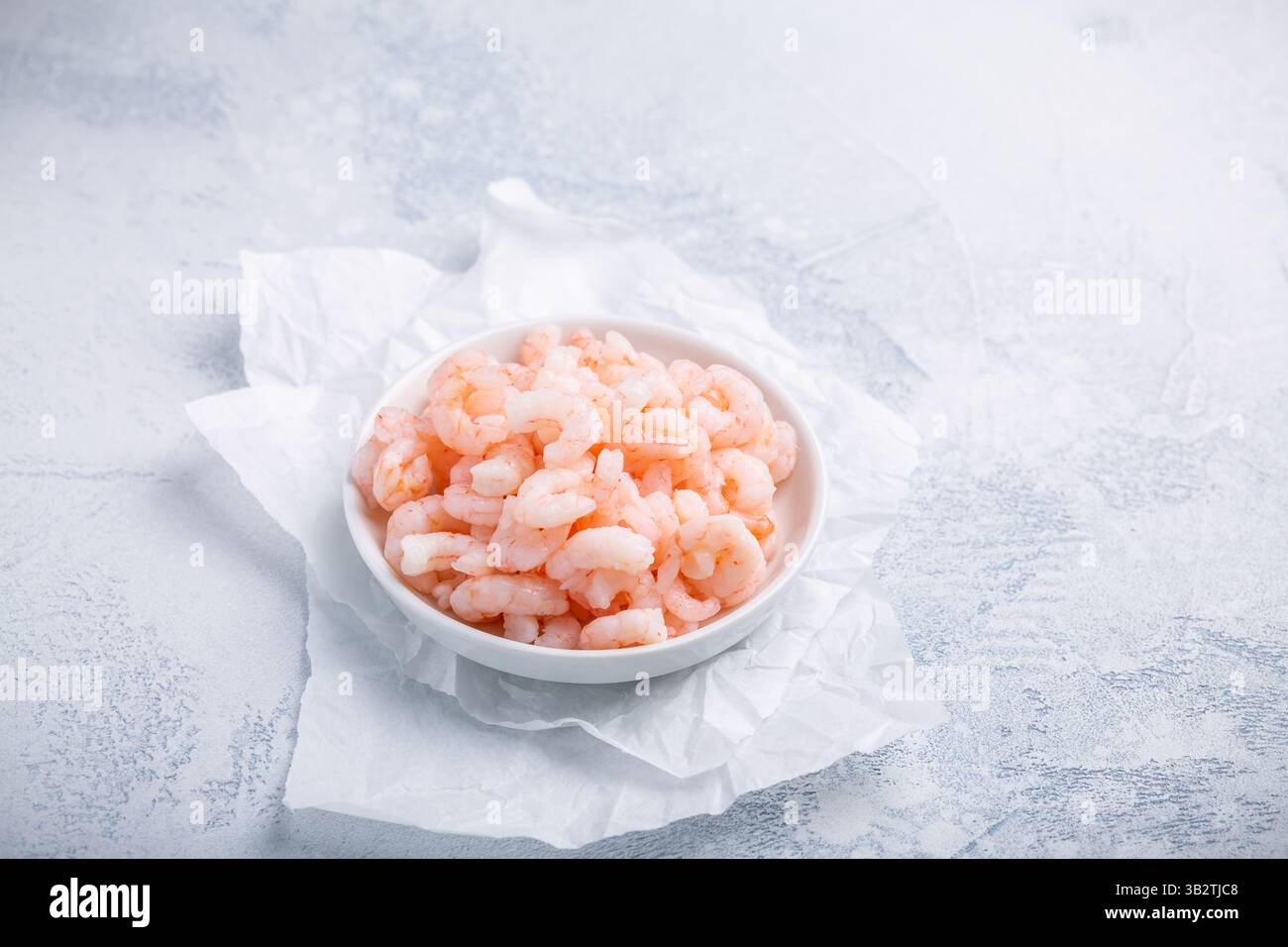 Schüssel mit gekochten kleinen geschälten Garnelen auf dem Küchentisch Stockfoto