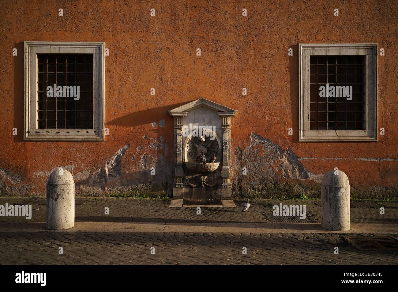 Ein klassischer römischer Brunnen leuchtet im goldenen Stundenlicht in der Nähe des Vatikans in Rom, Italien, mit Tauben, die leise auf dem verwitterten Stein thronen. Stockfoto
