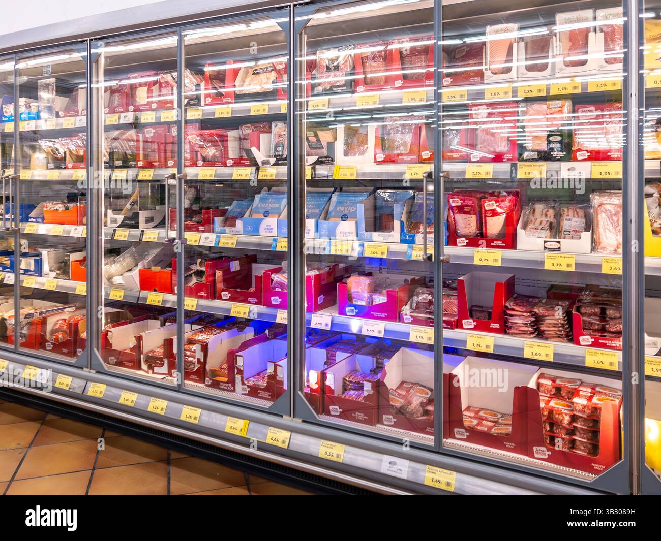 Italien - 26. April 2025: Packungen mit Schinken, Salami und aufgeschnittenem Fleisch werden in gekühlten Vitrinen zum Verkauf im italienischen Supermarkt ausgestellt Stockfoto