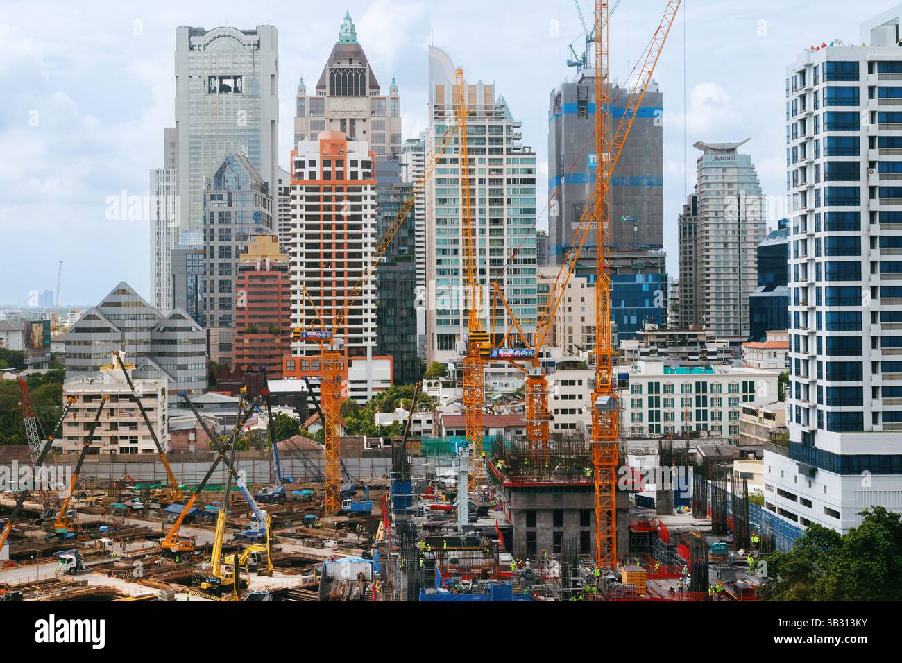 Bangkok, Thailand - 28. April 2025 : städtische Baustelle mit Kränen, Maschinen und Arbeitern, die aktiv Hochhäuser bauen, umgeben von Stockfoto
