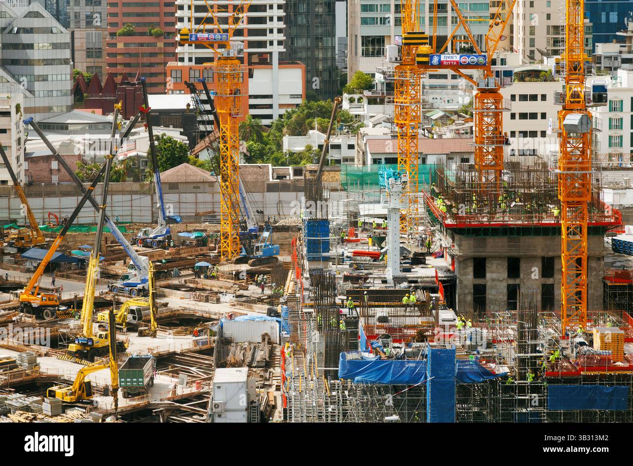 Bangkok, Thailand - 28. April 2025 : städtische Baustelle mit Kränen, Maschinen und Arbeitern, die aktiv Hochhäuser bauen, umgeben von Stockfoto