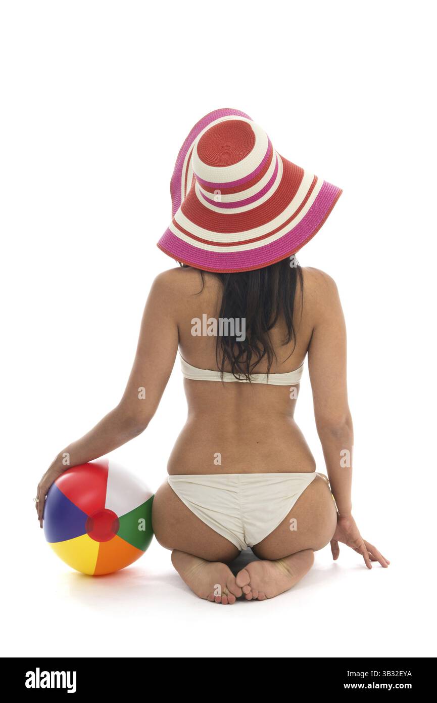 Schlanke schwarze Frau sitzen am Strand mit Ball isoliert auf weißem Hintergrund Stockfoto