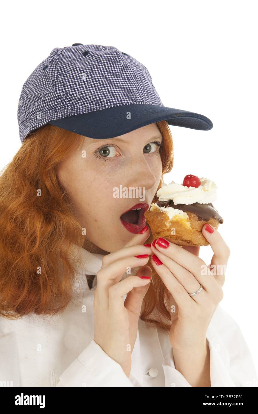 Back-Küchenfrau mit rotem Haar, das Gebäck über weißem Hintergrund isst Stockfoto