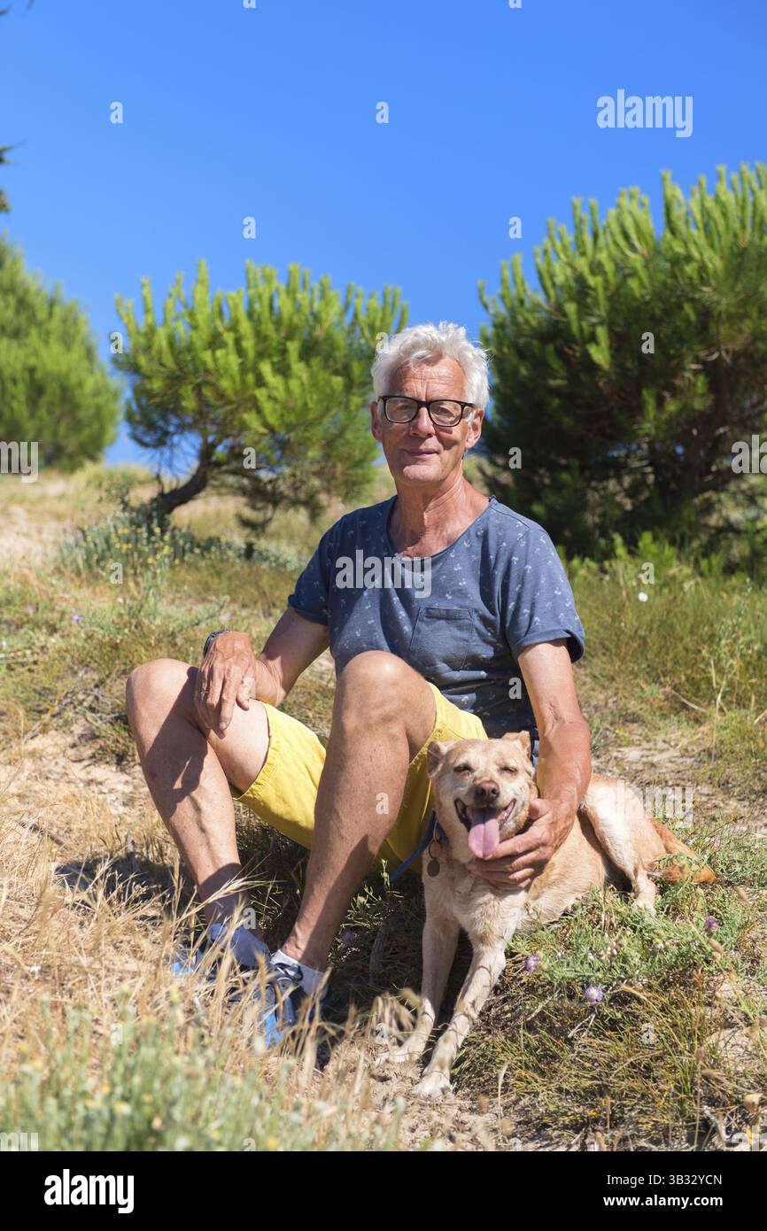 Ile de Re - älterer Mann sitzen zusammen mit Hund in den Dünen Stockfoto