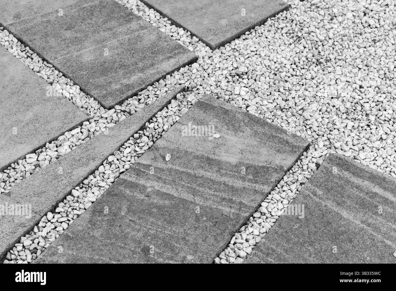 Einfarbiges Foto mit strukturierten Pflasterplatten im eleganten Kontrast zu kleinem, verstreuten Kies Stockfoto