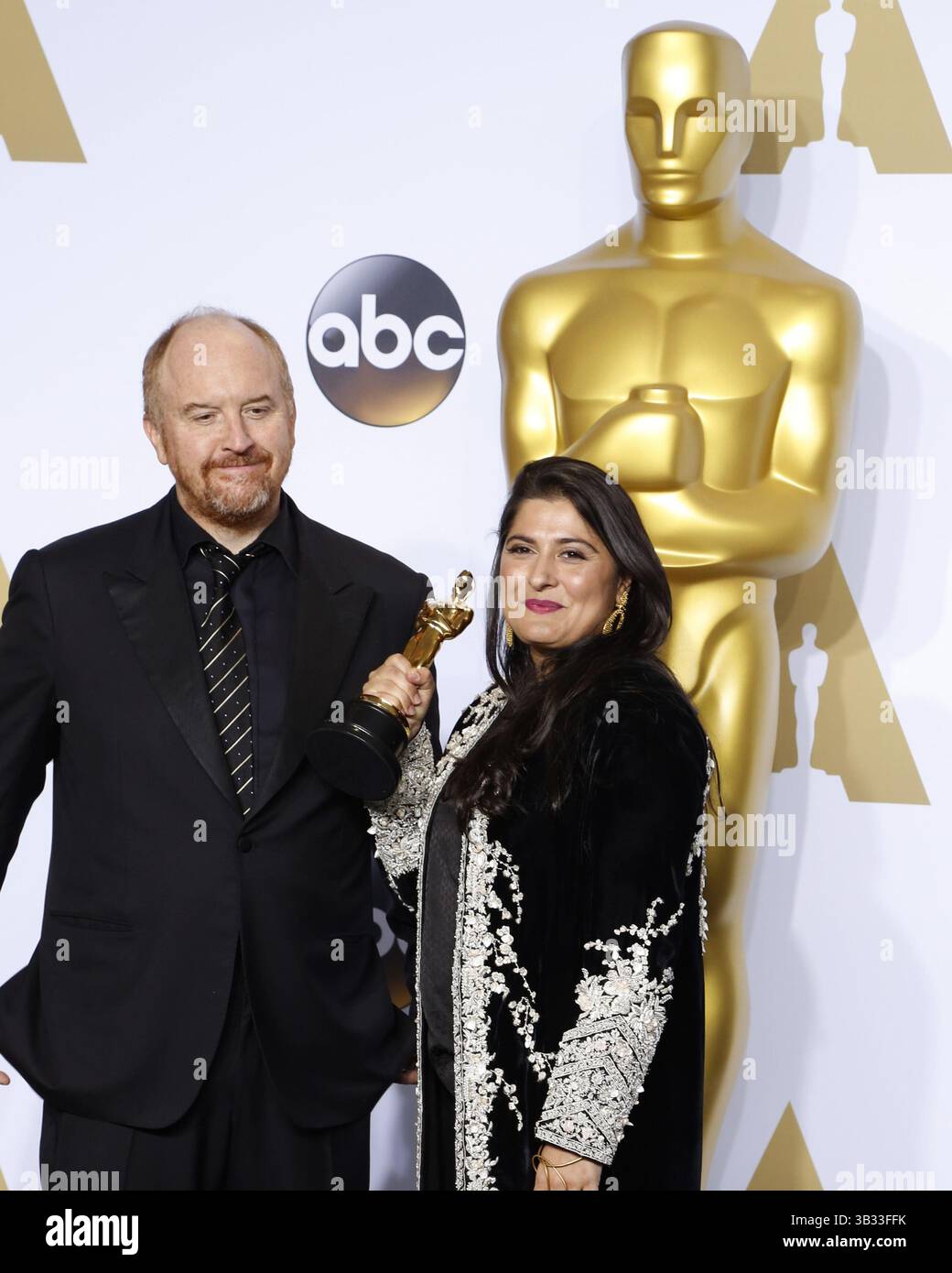 29. Februar 2016 - Los Angeles, CA, USA - LOS ANGELES - 28. Februar: Louis C.K., Sharmeen Obaid-Chinoy bei den 88. Annual Academy Awards - Pressesaal im Dolby Theater am 28. Februar 2016 in Los Angeles, CA Foto via Newscom (Credit Image: © hPa/Newscom via ZUMA Press) Stockfoto