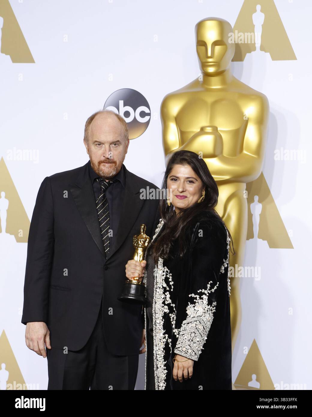 29. Februar 2016 - Los Angeles, CA, USA - LOS ANGELES - 28. Februar: Louis C.K., Sharmeen Obaid-Chinoy bei den 88. Annual Academy Awards - Pressesaal im Dolby Theater am 28. Februar 2016 in Los Angeles, CA Foto via Newscom (Credit Image: © hPa/Newscom via ZUMA Press) Stockfoto