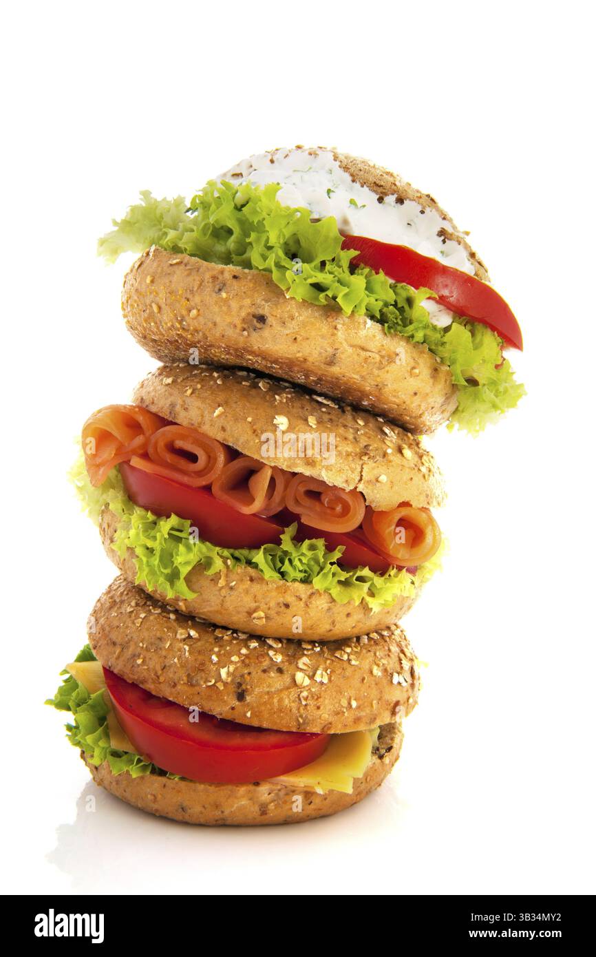 Drei frische Bagels mit luxuriösen Aufstrichen auf weißem Hintergrund Stockfoto