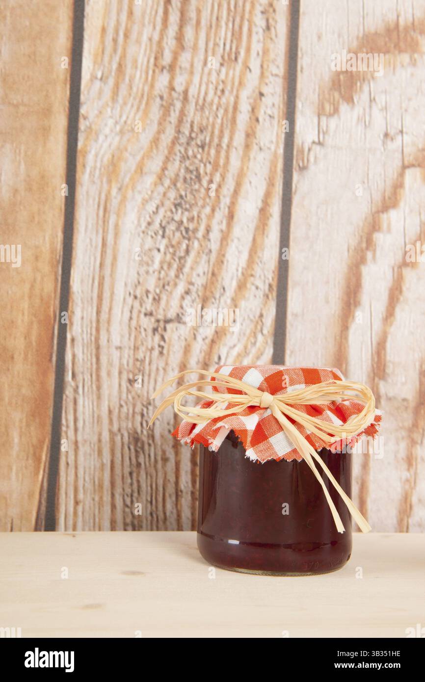 Selbstgemachte Marmelade im Glastopf mit hölzernem Hintergrund Stockfoto