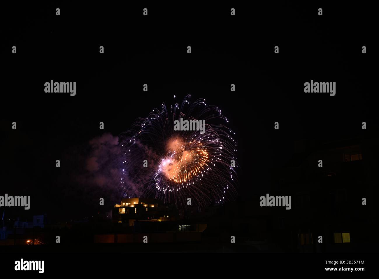 Ein glitzerndes buntes Feuerwerk erleuchtet den Nachthimmel während einer festlichen Feier. Stockfoto